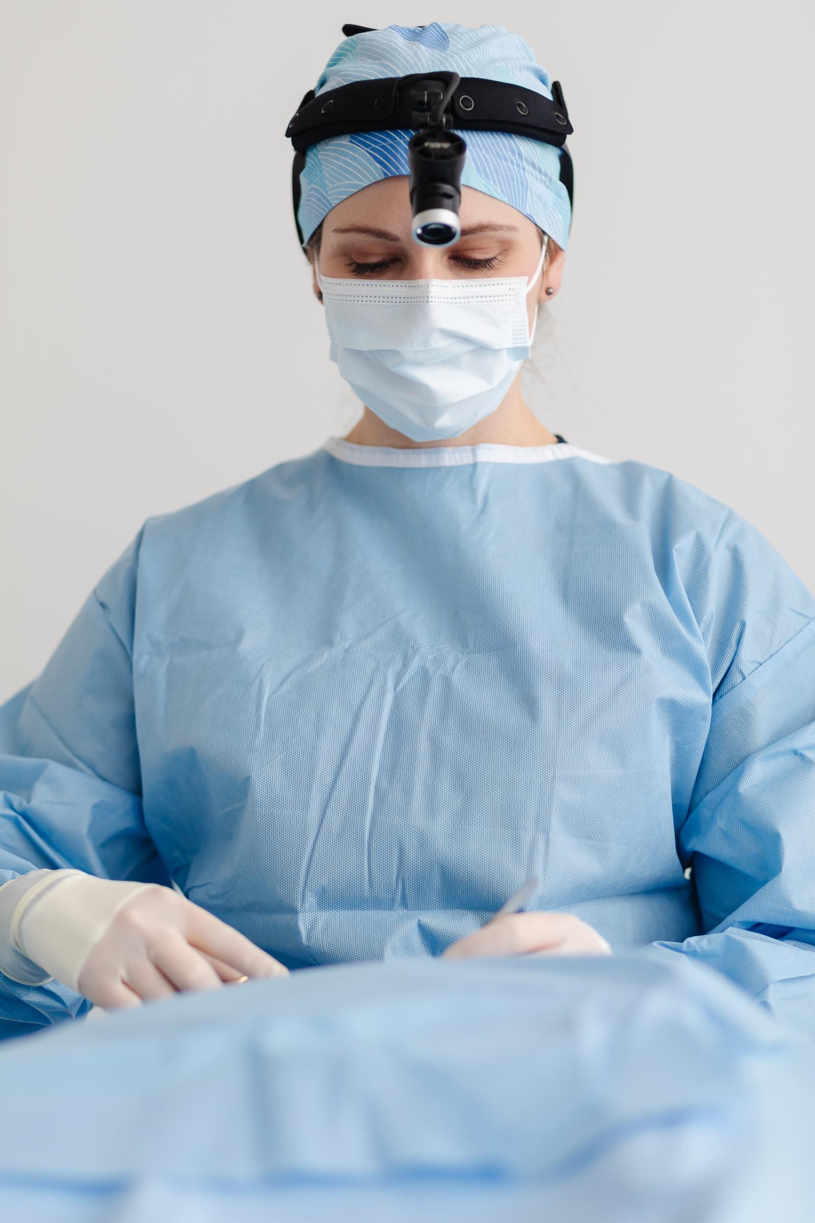 Photo of Dr. Hamil in full surgical scrubs looking down at an operating table. 